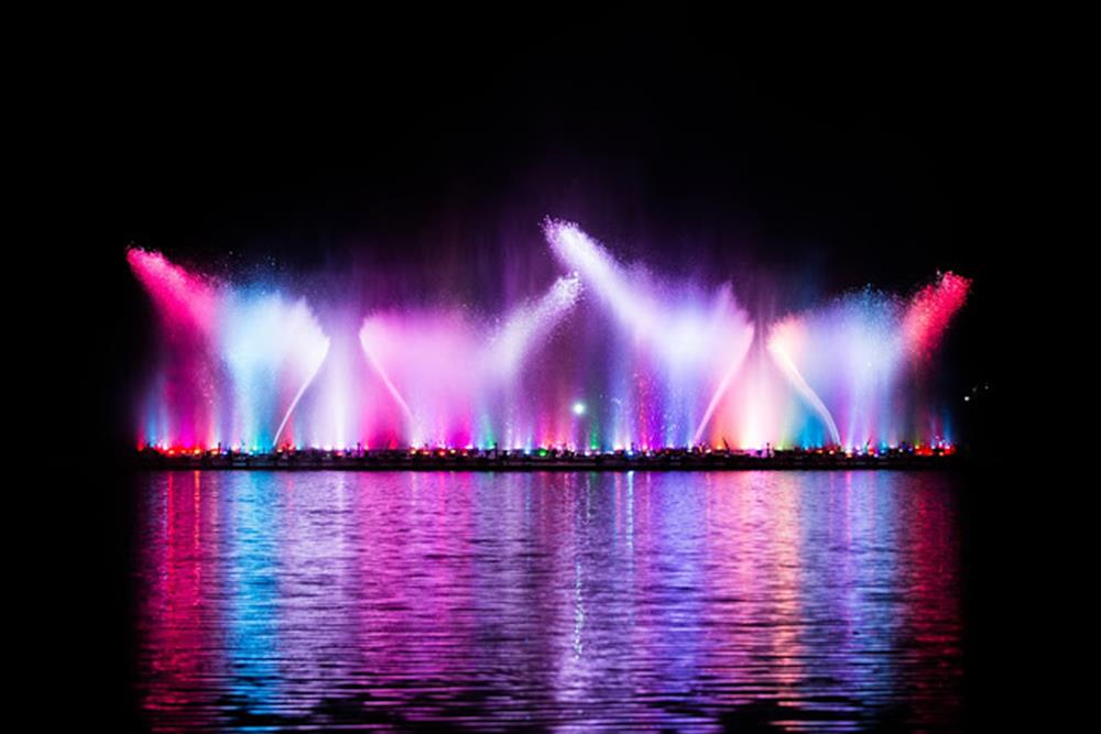 Beautiful fountain show with reflection on water at night.