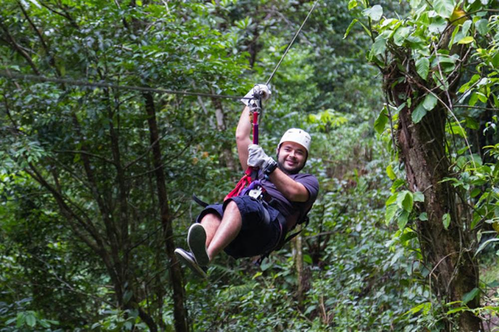 young man zooming thru a cloud forest on a zip line adventure in Monteverde Costa Rica